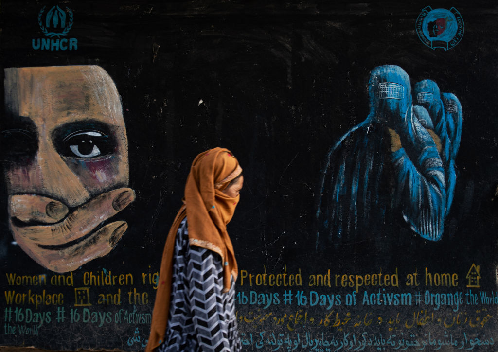A woman walks past a mural calling for women and children's rights in Afghanistan.