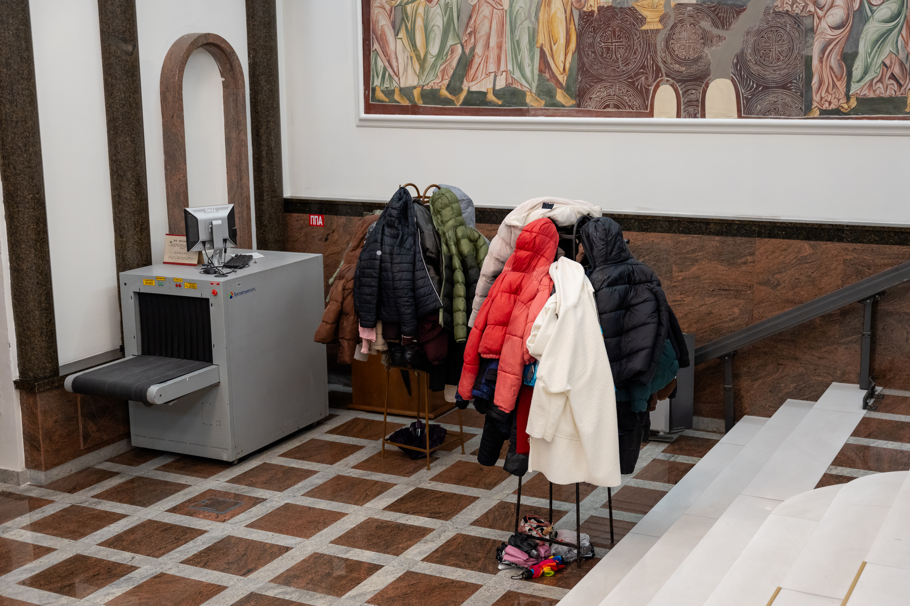 Un portemanteau avec différentes vestes se trouve à côté d'un scanner de sécurité.