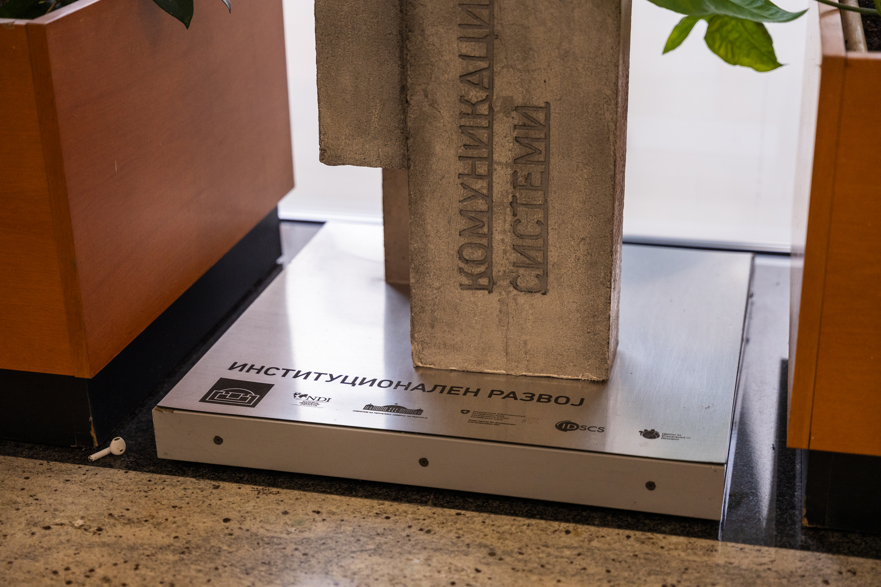 Sculpture en béton avec texte gravé sur un socle métallique portant les logos des instituts
