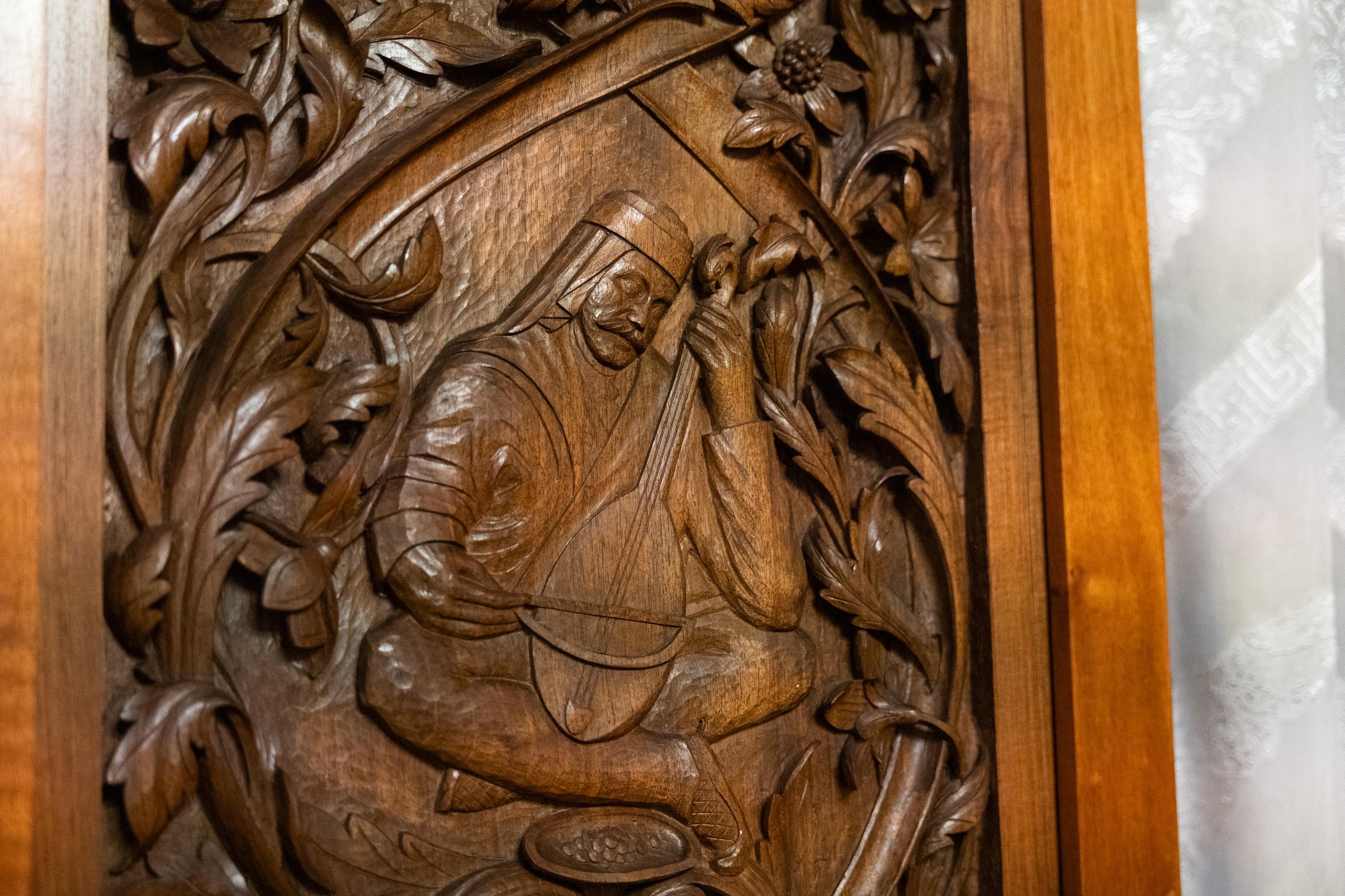 Une sculpture sur bois accrochée au mur représentant une personne jouant d'un instrument.