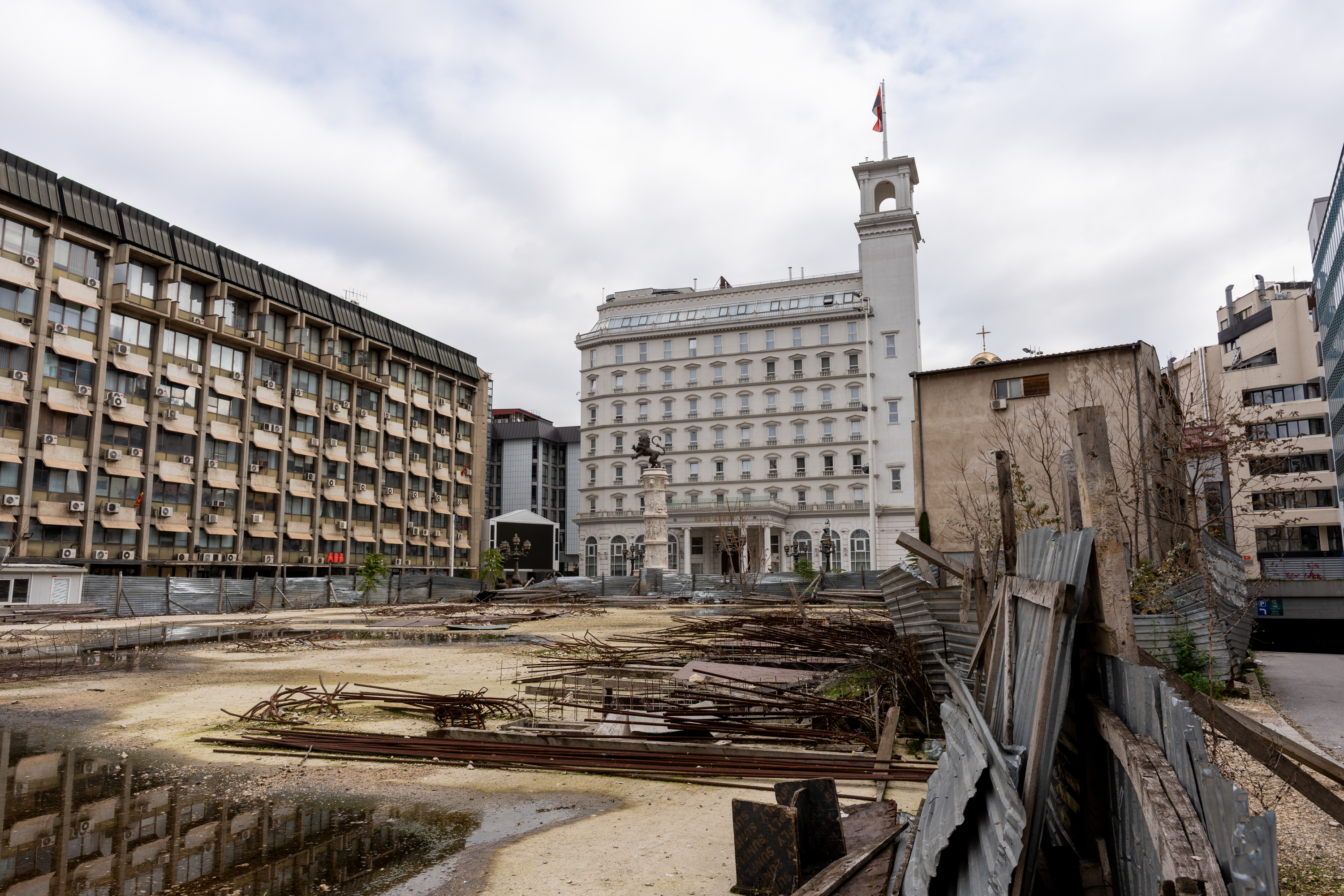 Grand bâtiment blanc avec un drapeau sur le toit, au premier plan un chantier