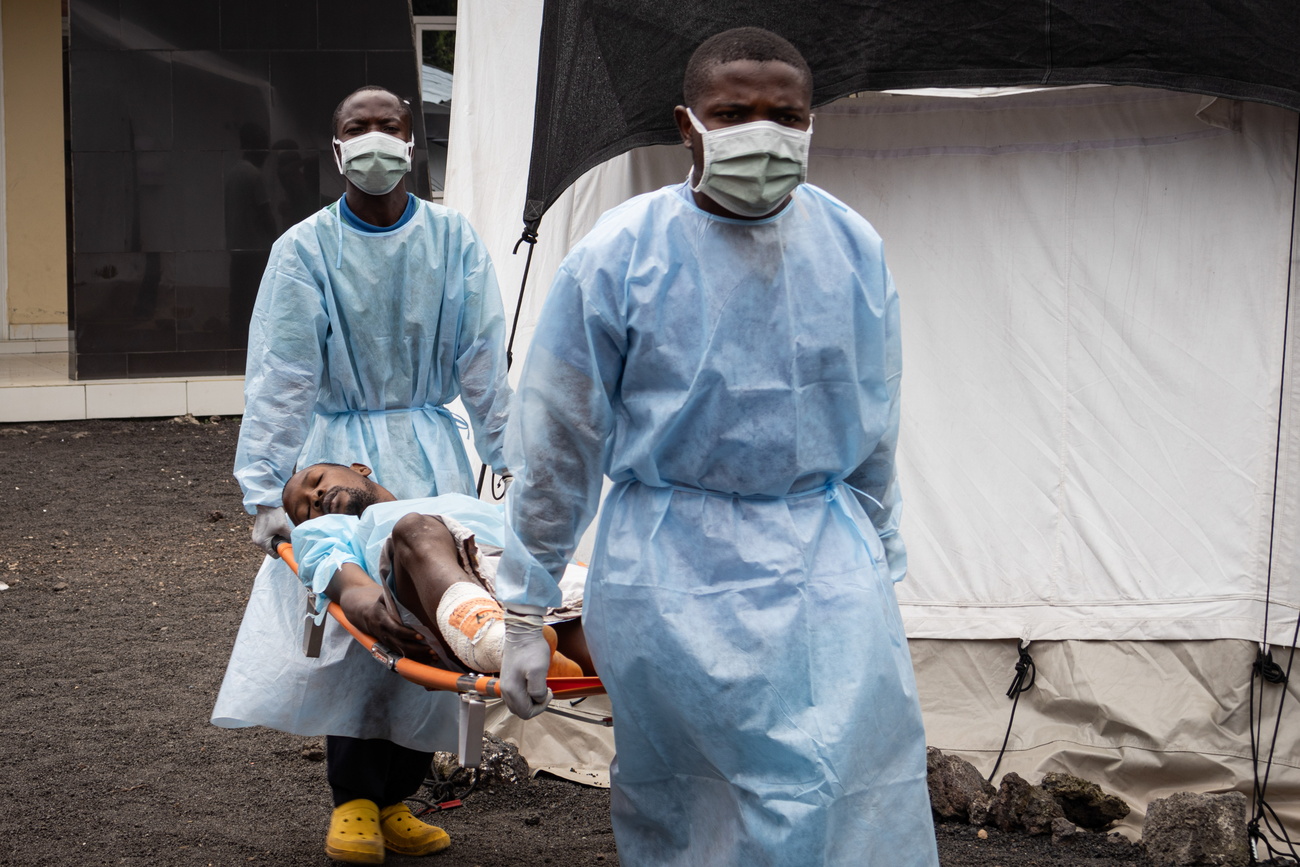 Two men carry a man on a stretcher.