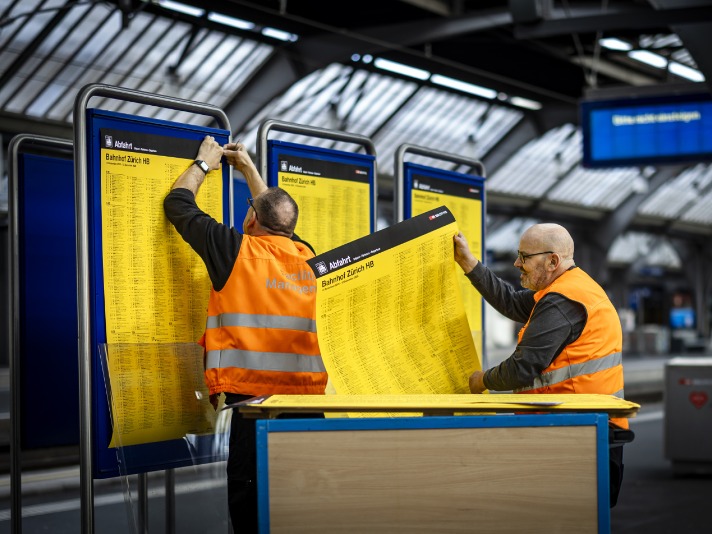 operai cambiano cartellone degli orari in una stazione ferroviaria svizzera