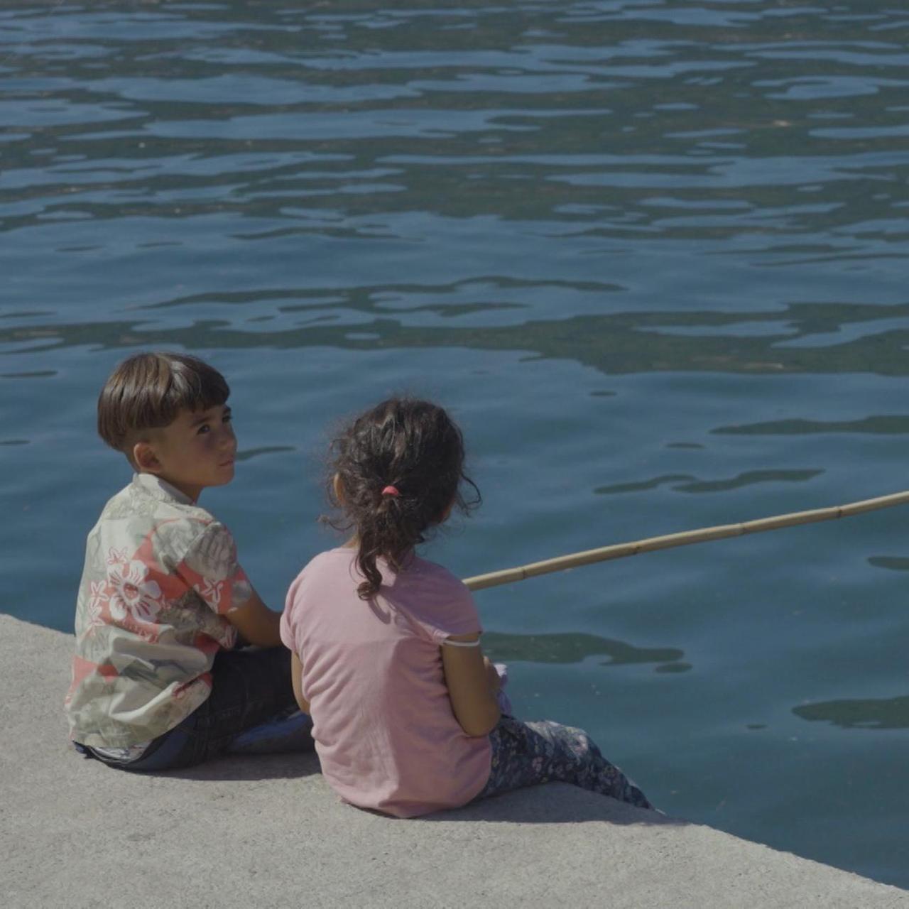Ali et Maria pêchent dans le port de Samos, espérant trouver du poisson.
