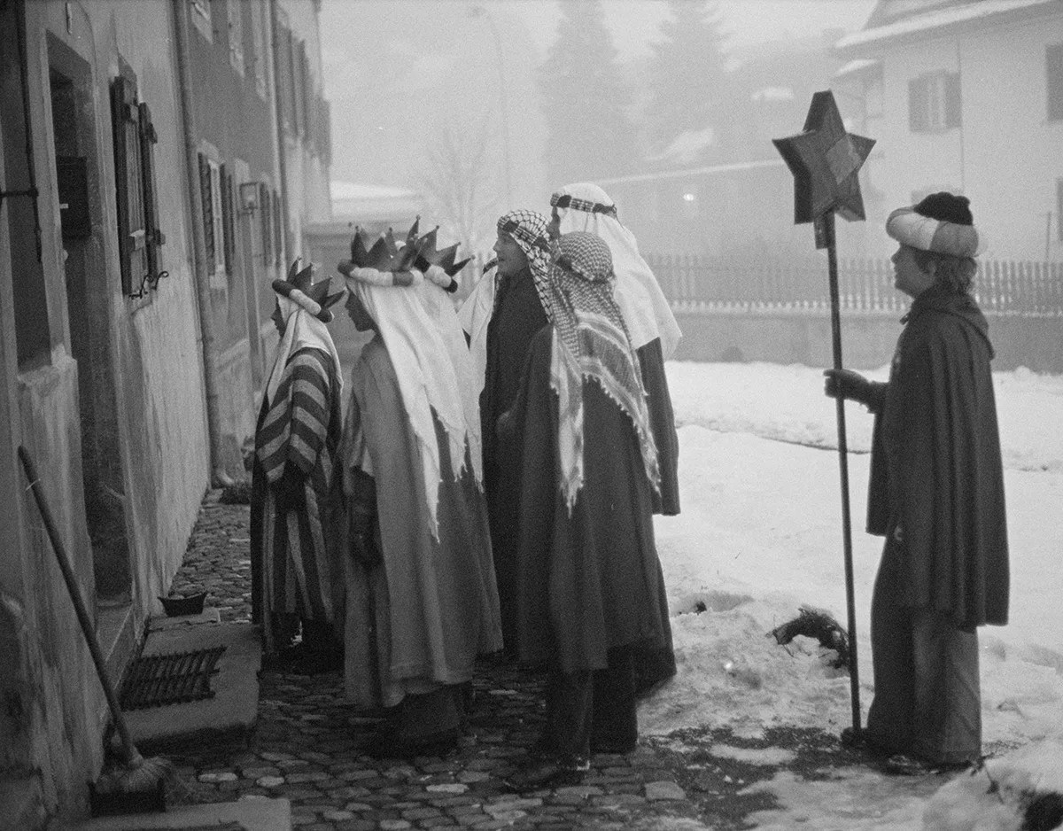 Kinder, die die Heiligen Drei Könige darstellen, vor einer Tür in einer Straße