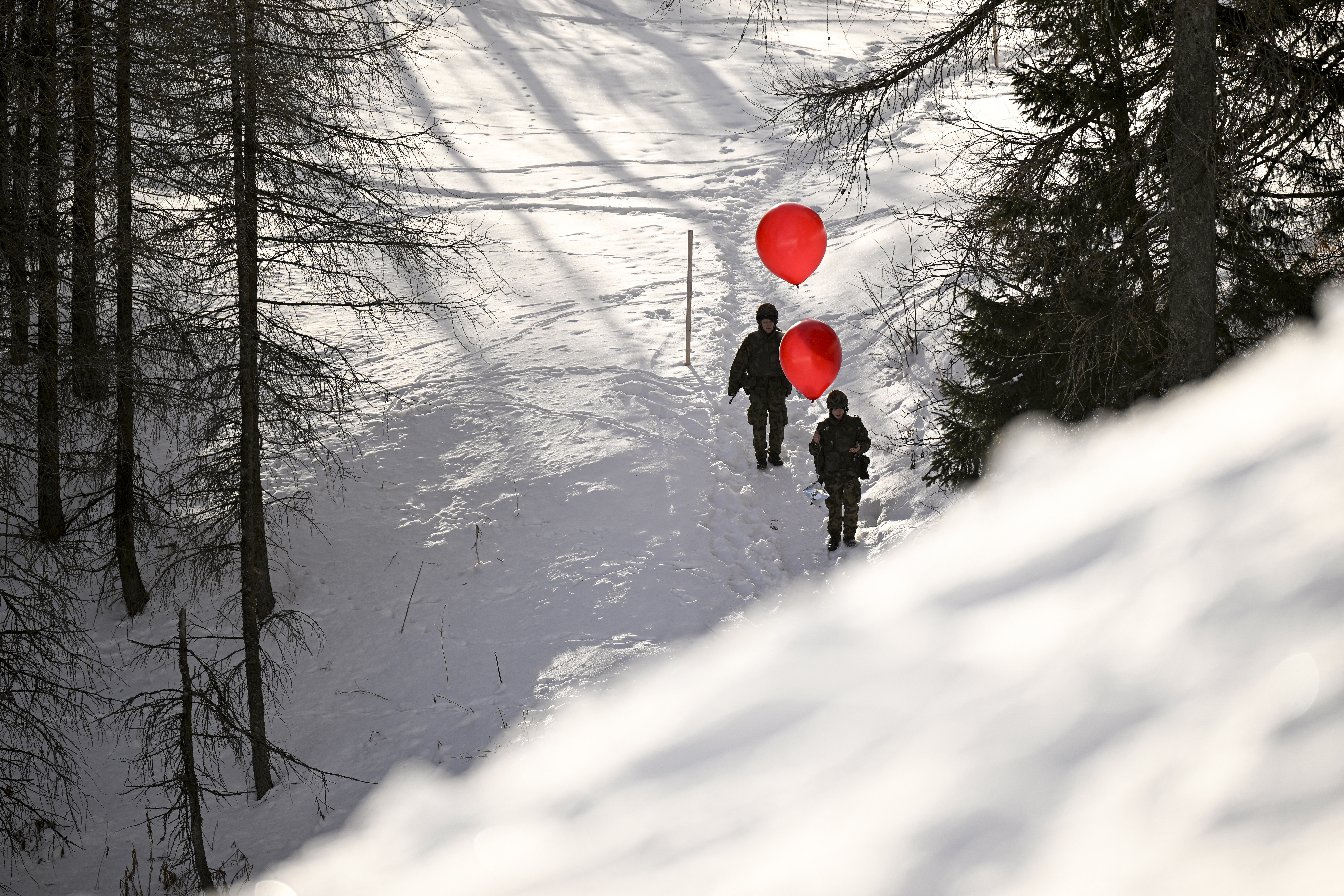 Militari con palloni meteorologici camminano nella neve durante il Forum economico mondiale (WEF) a Davos, il 22 gennaio 2026.