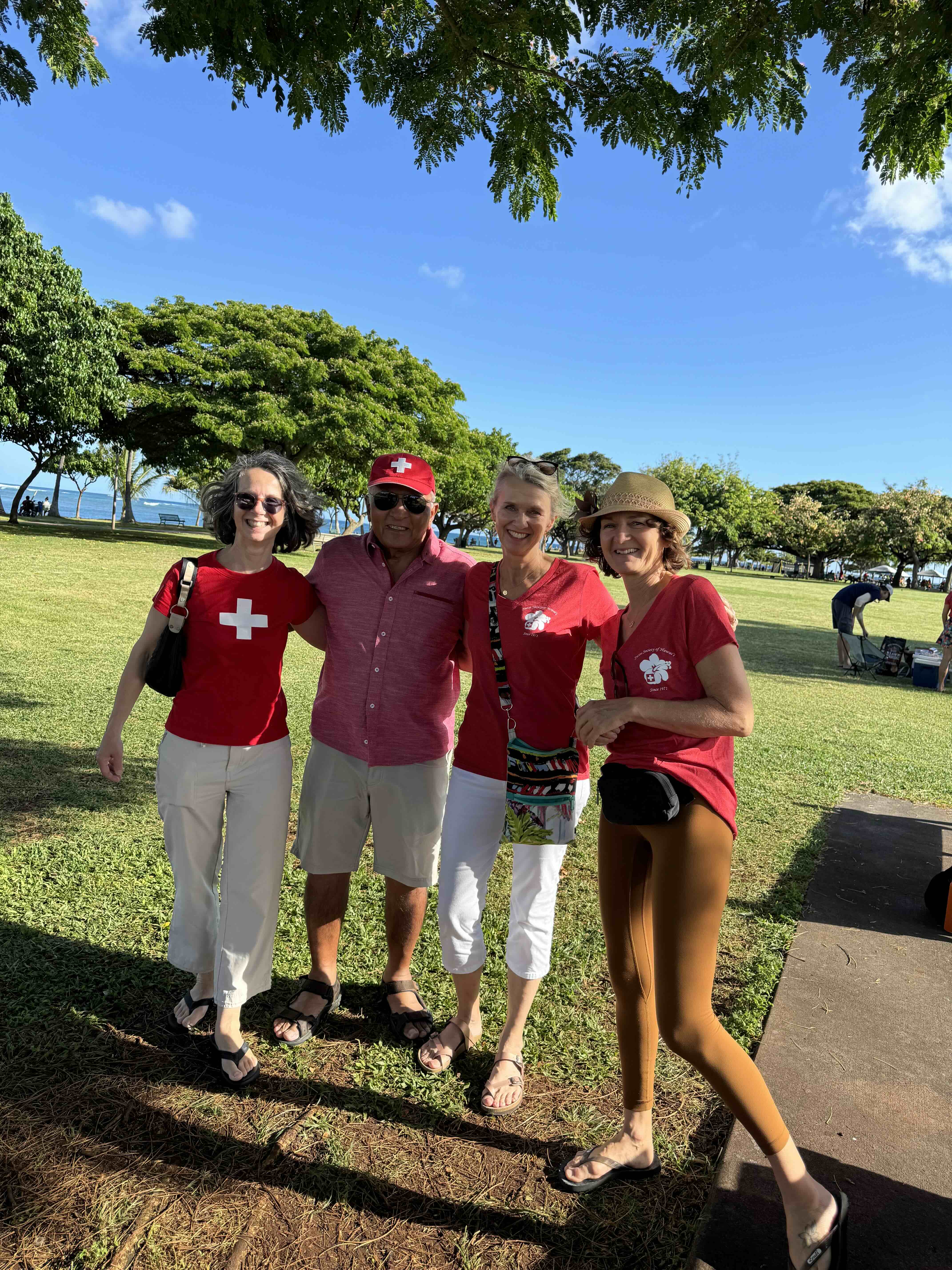 Trois femmes et un homme, les femmes portent des t-shirts Suisse, l'homme porte une casquette Suisse.