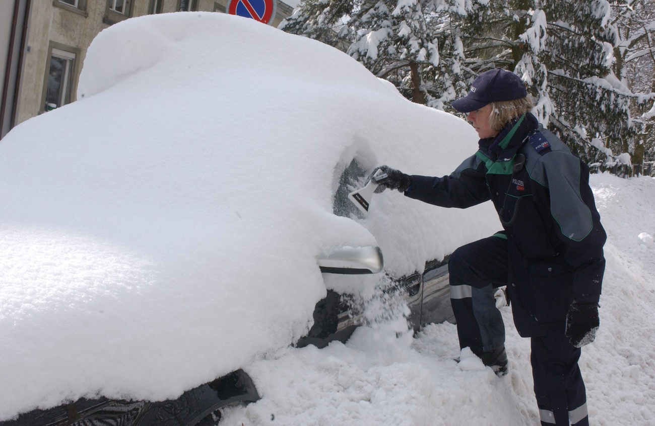 Un’agente svizzera scava nella neve alla ricerca della ricevuta di pagamento del parcheggio.