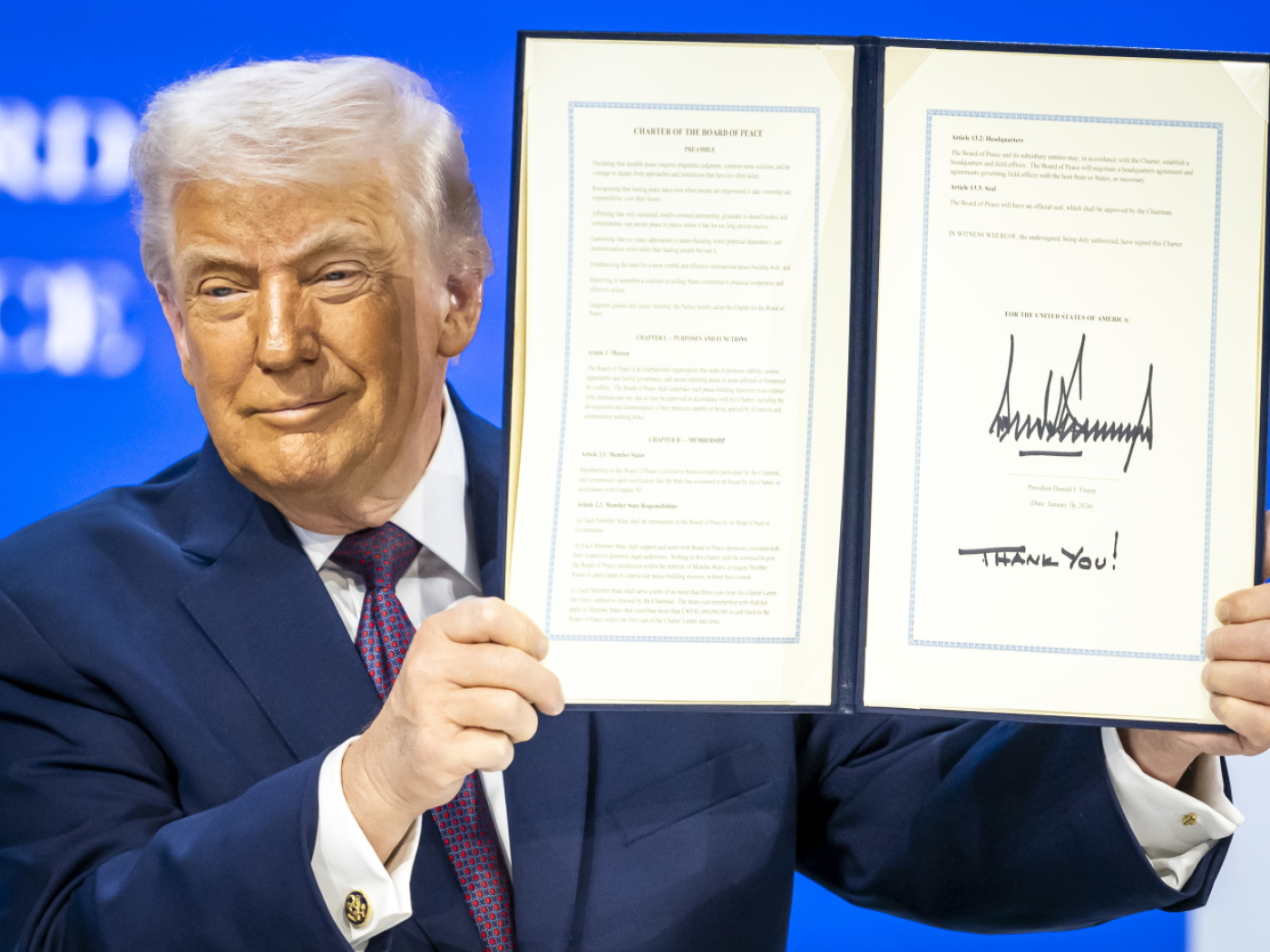 trump mostra la sua enorme firma che sigilla l'atto di creazione del Consiglio per la Pace