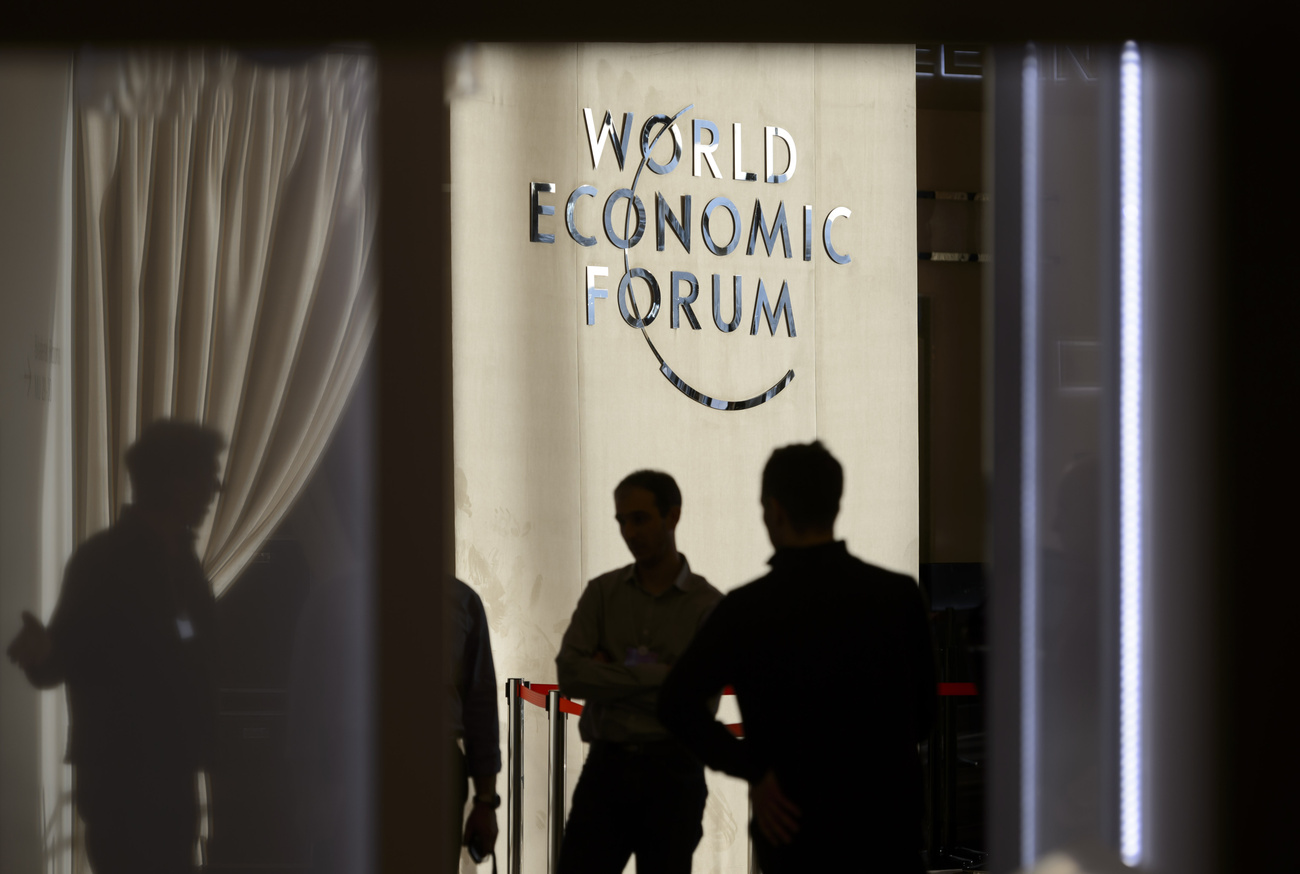 Teilnehmende diskutieren vor einem großen WEF-Logo im Inneren des Kongresszentrums in Davos, kurz vor Beginn der 46. Jahrestagung des Weltwirtschaftsforums im Januar 2016.