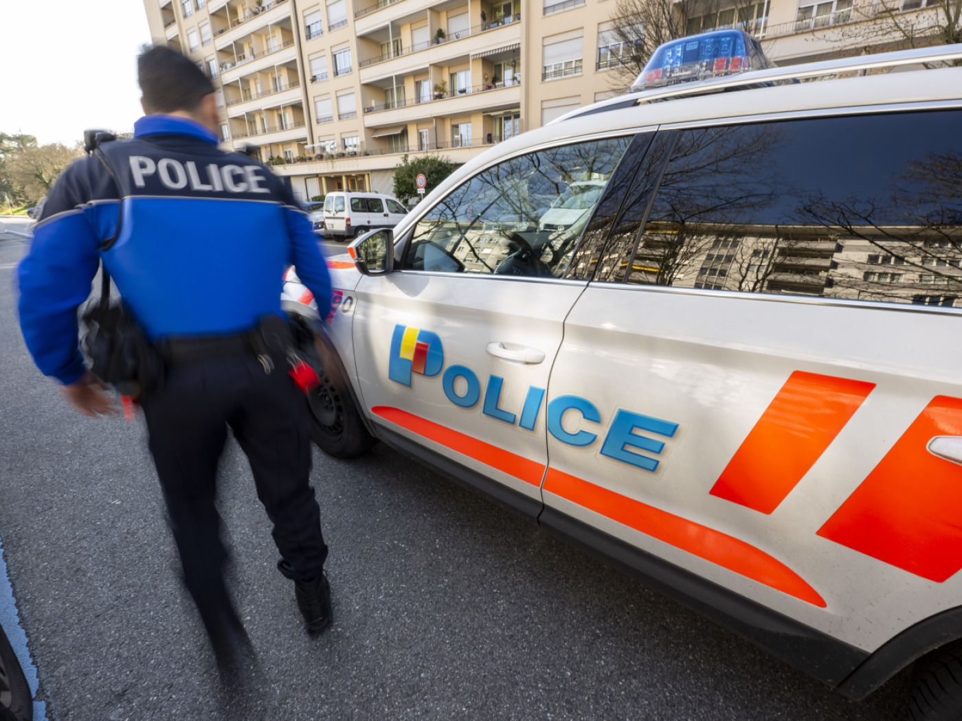 agente polizia di ginevra accanto ad auto di pattuglia