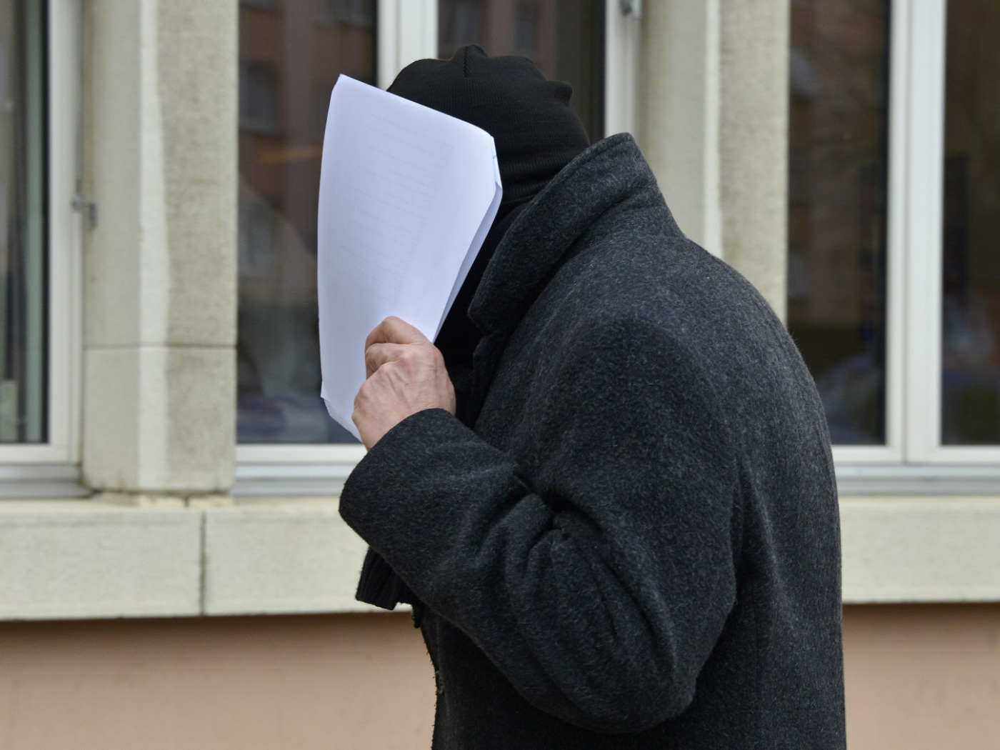 uomo si nasconde dietro fogli che tiene in mano