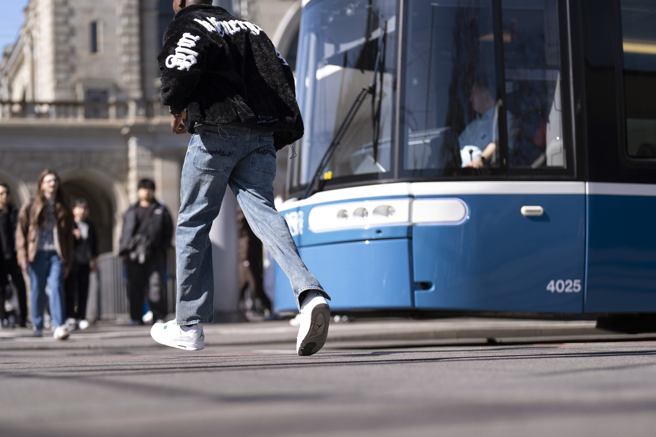 A young man runs in front of a tram in Zurich.