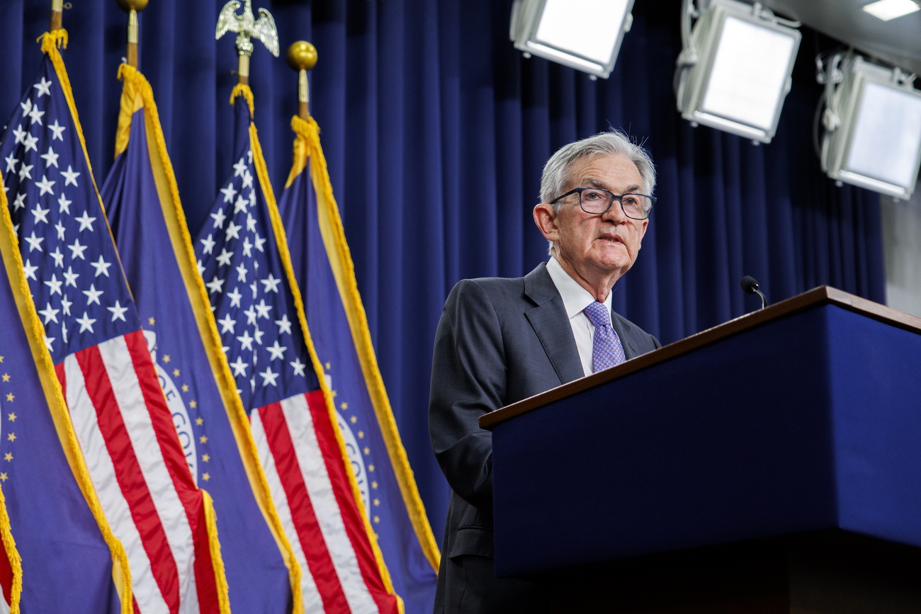 Ein Mann im Anzug an einem Rednerpult vor mehreren US-Flaggen