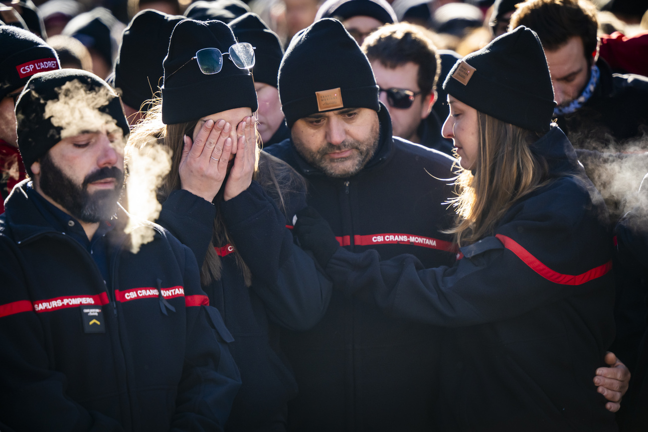 Des pompiers de Crans-Montana – les premiers sur les lieux de l’incendie – se recueillent dimanche autour des fleurs et des bougies déposées pour les victimes.
