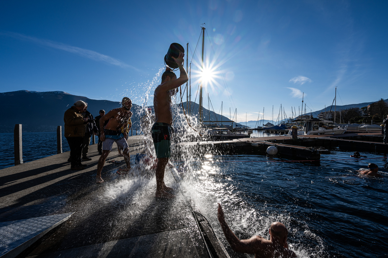 Persona in riva al lago si versa un secchio d'acqua in testa