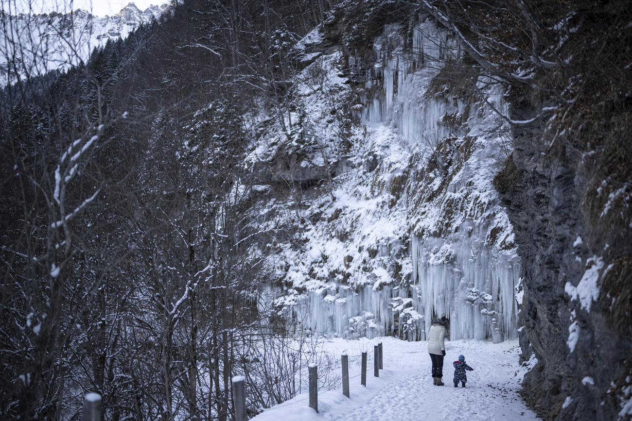 una donna e un bambino camminano lungo una strada innevata in montagna