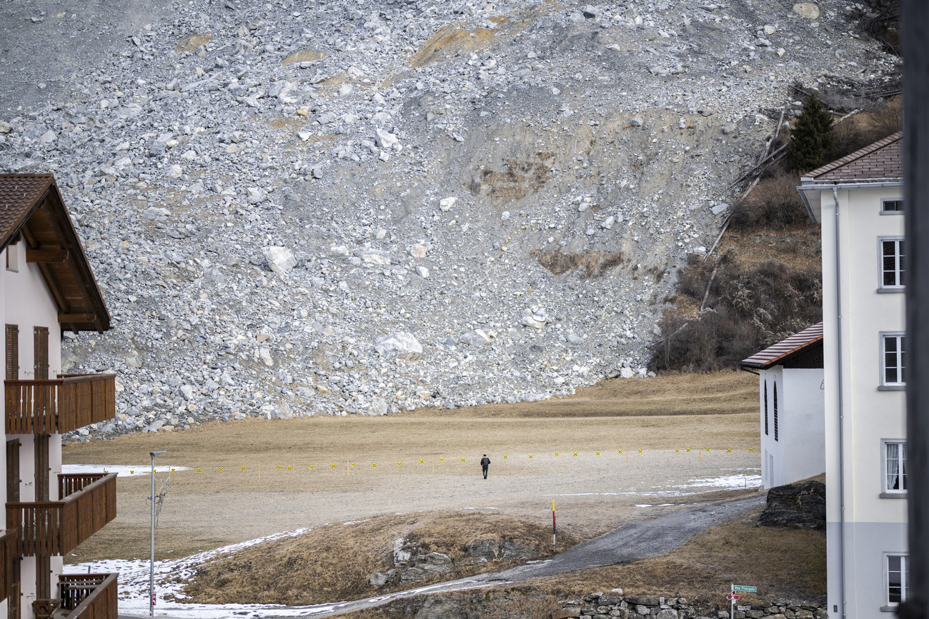 Persona cammina davanti a parete montana con colata detritica