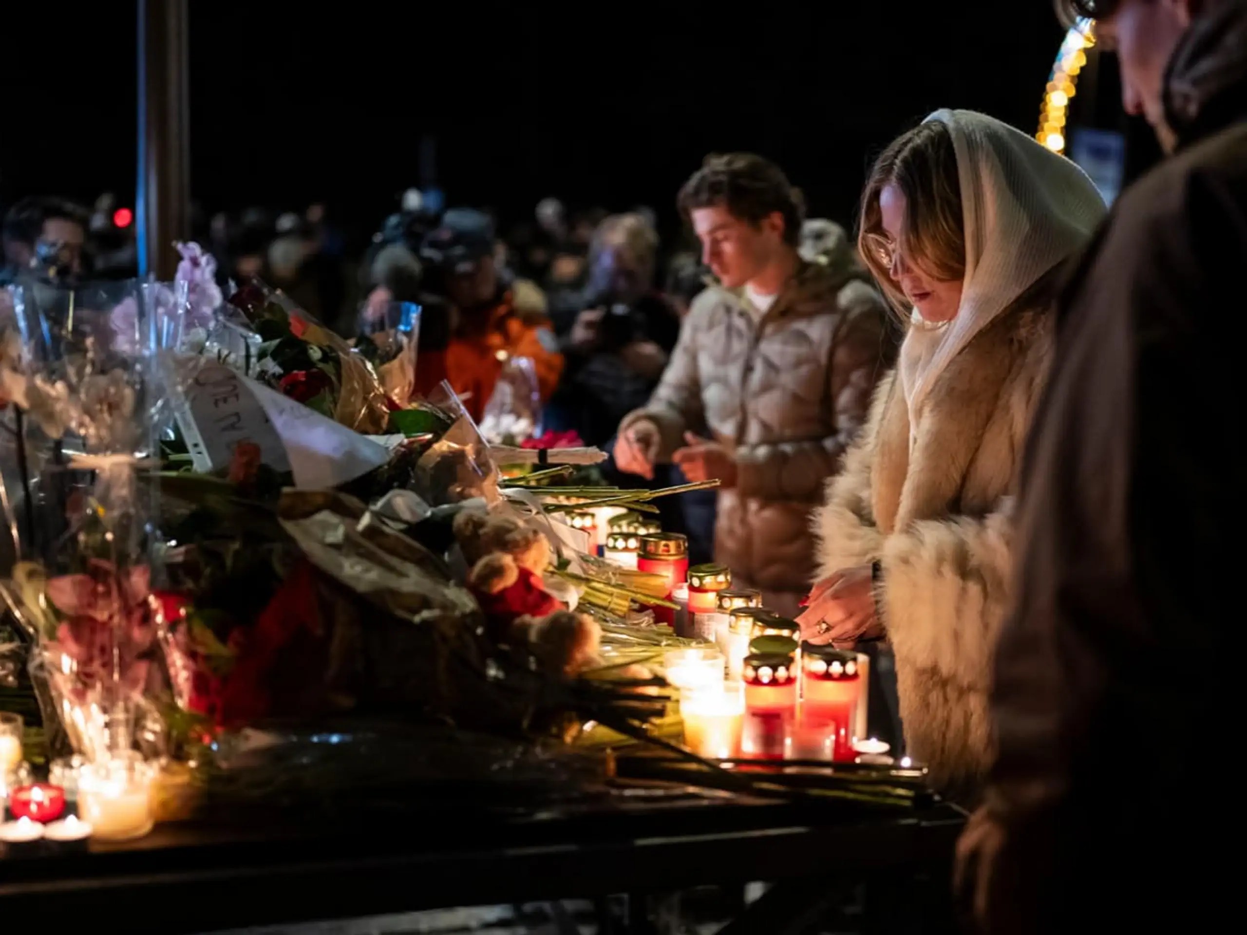 Menschen legen Blumen und Kerzen hin