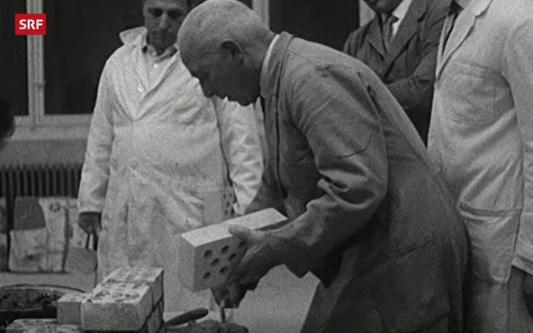 Mann legt einen Backstein auf den Kamin, den er baut