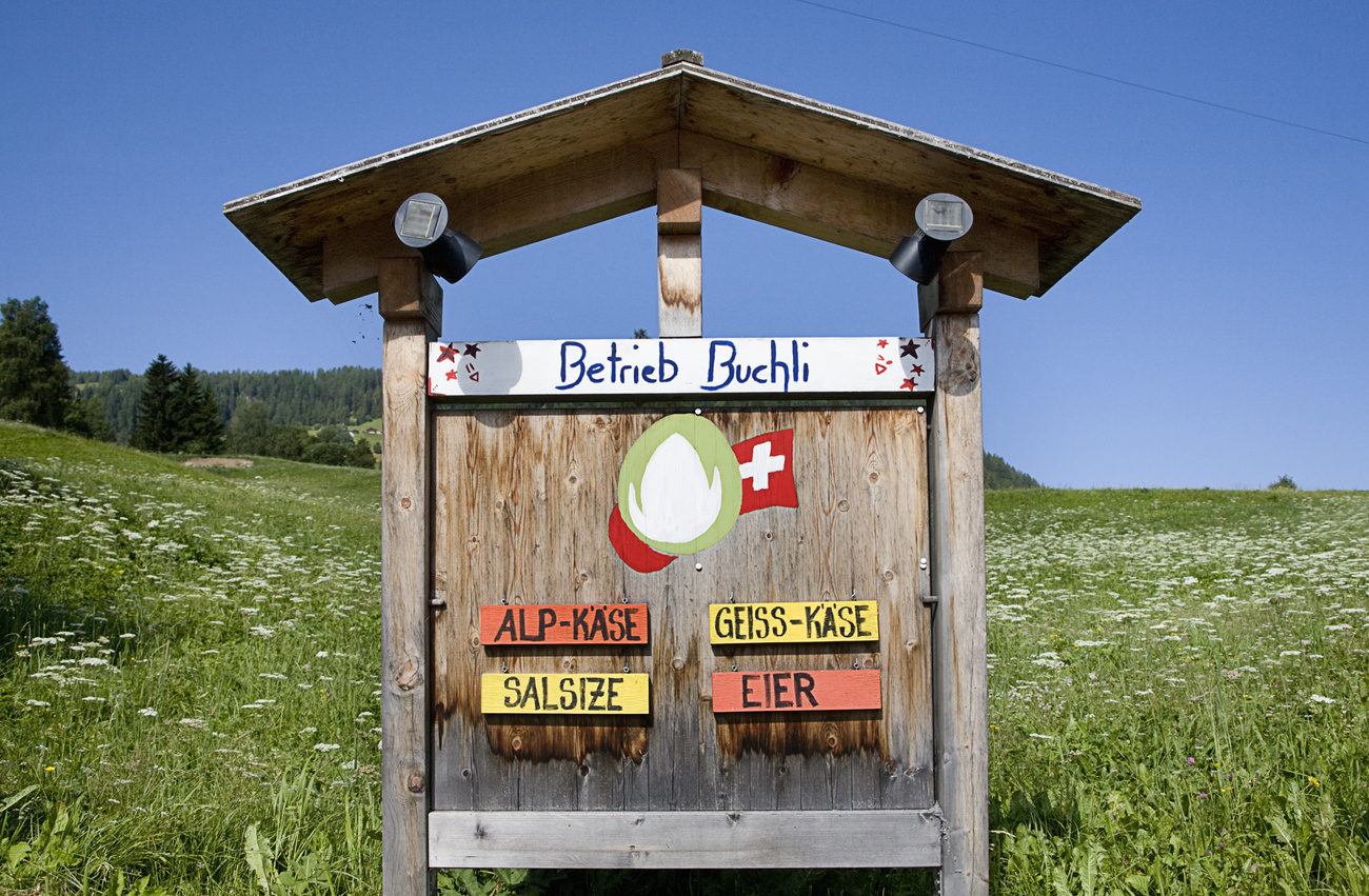 A sign in the shape of a small house draws attention to agricultural products.