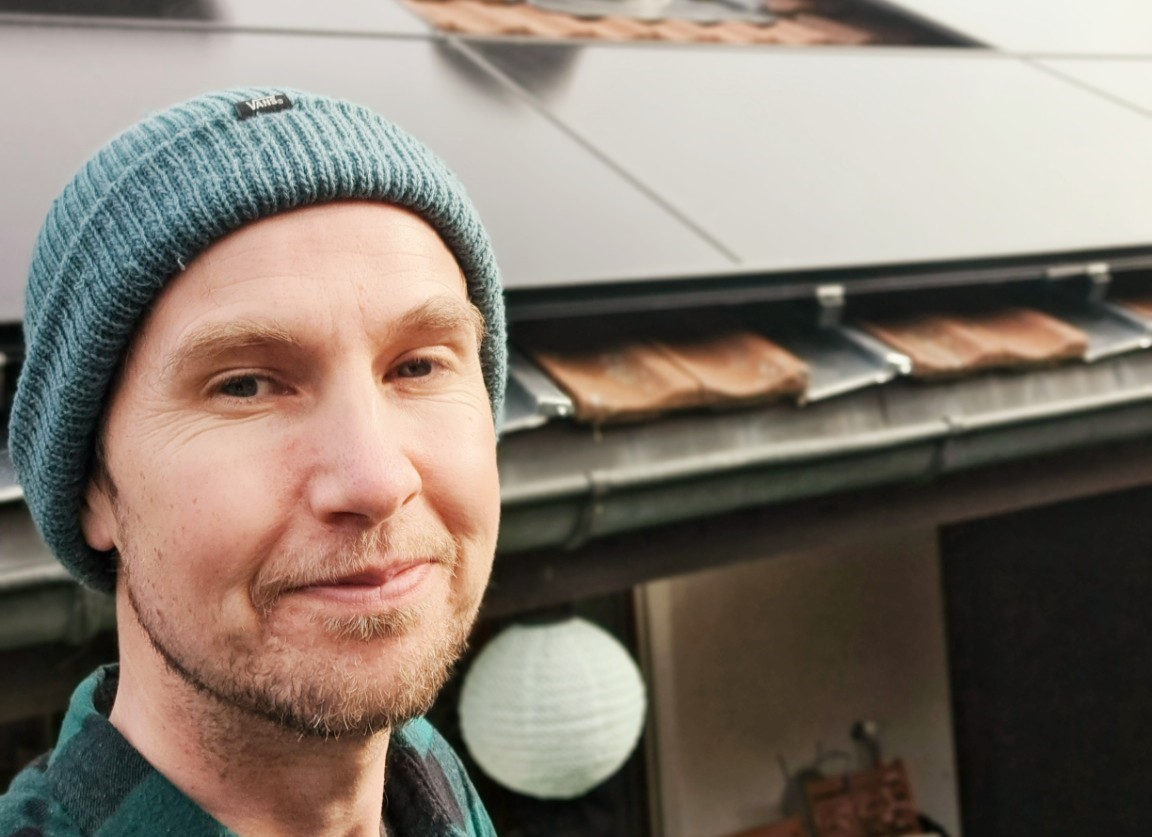 A Swiss homeowner stands beneath rooftop solar panels installed on a residential house in Switzerland.