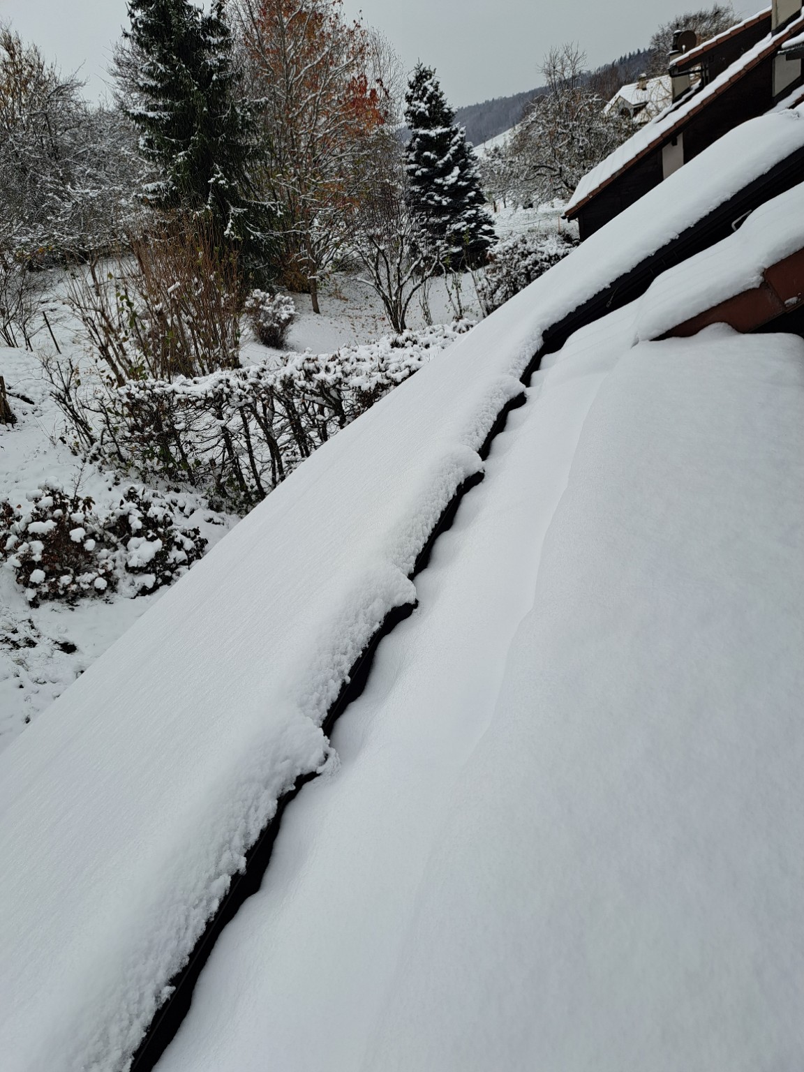 Solar panels on a sloped roof covered by a thick layer of snow, preventing electricity generation during winter.