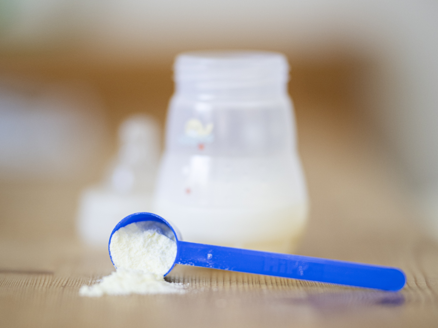 cucchiaino di latte in polvere accanto a biberon