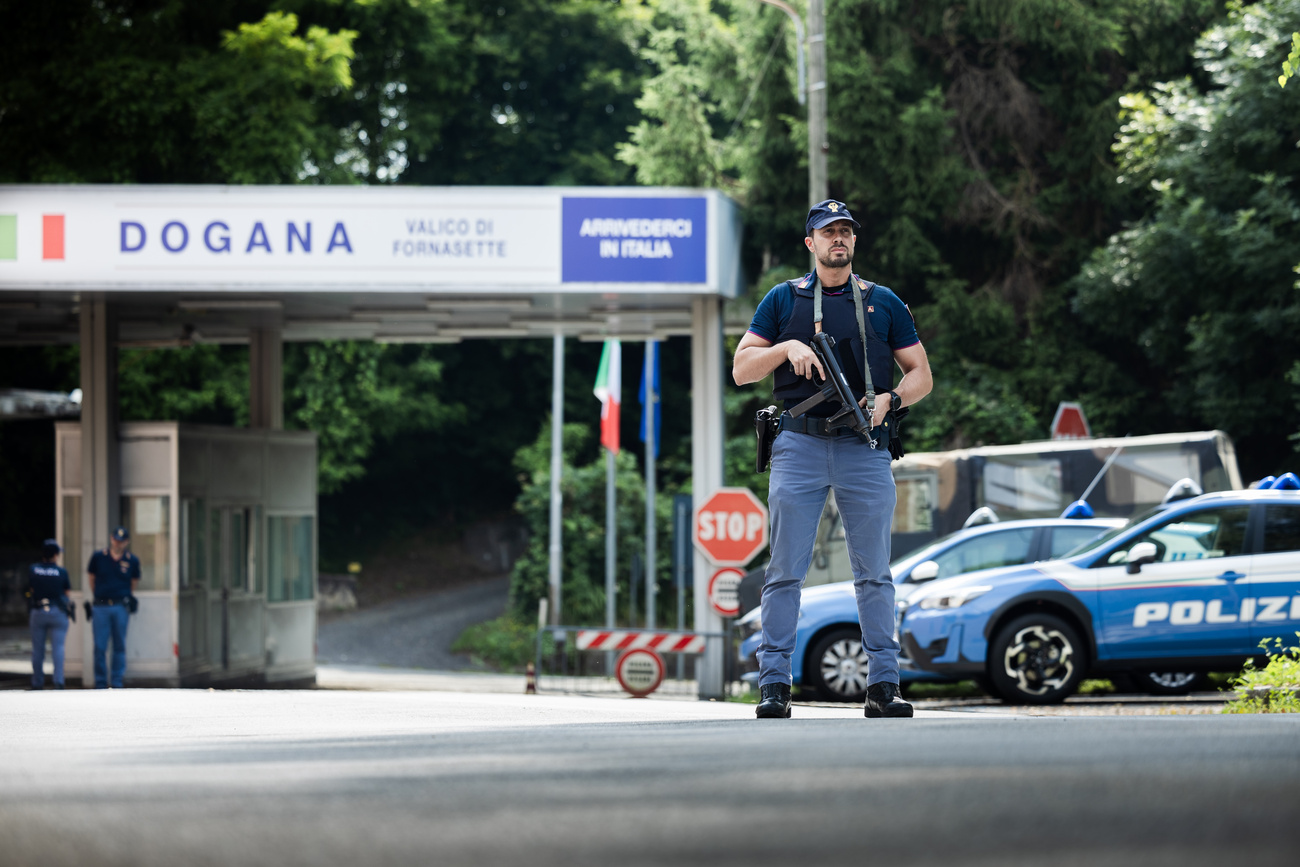 Un poliziotto italiano armato presidia un valico di frontiera tra Svizzera e Italia.