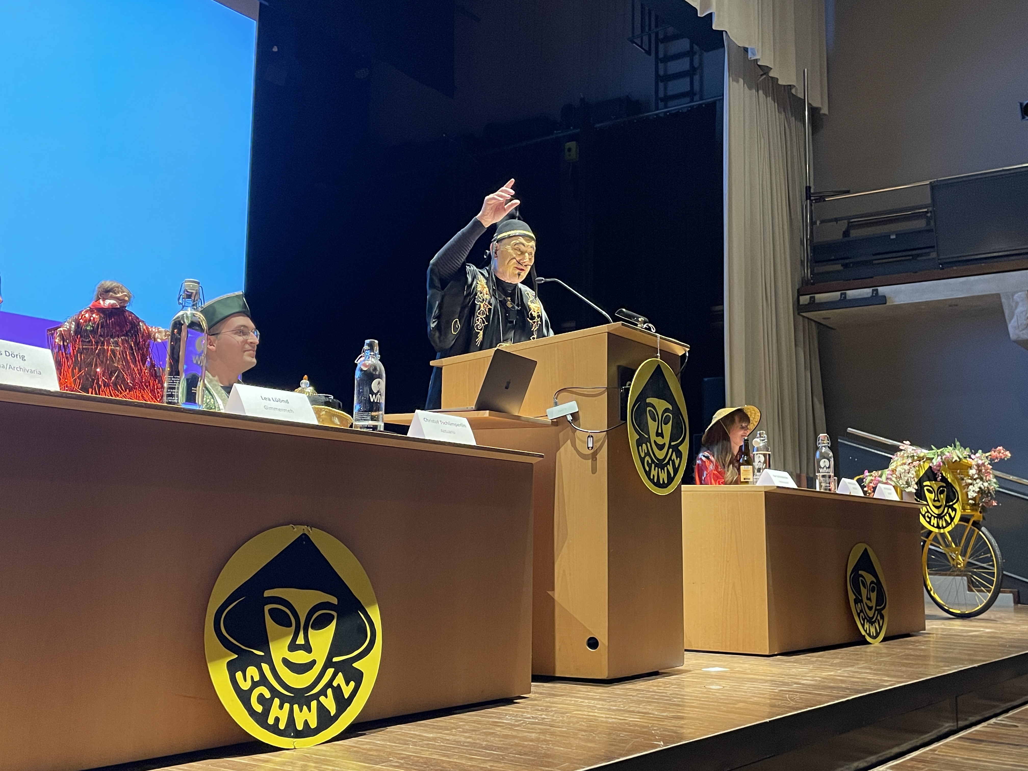 Ein Mann, der auf der Bühne seine rechte Hand hebt