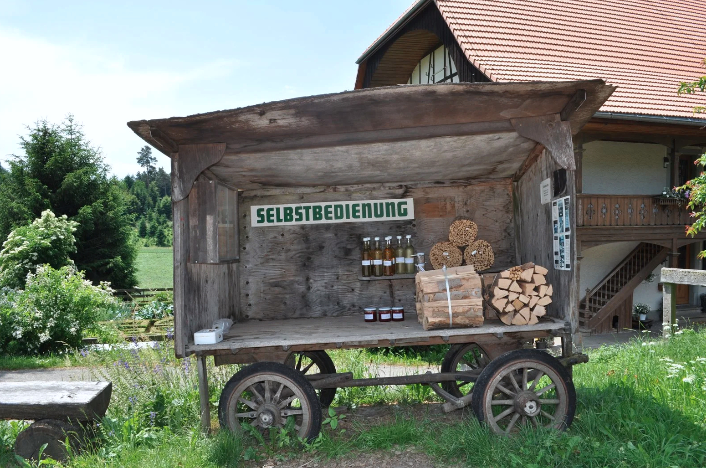 A wooden trailer displaying agricultural goods for sale, next to it a small cash box.