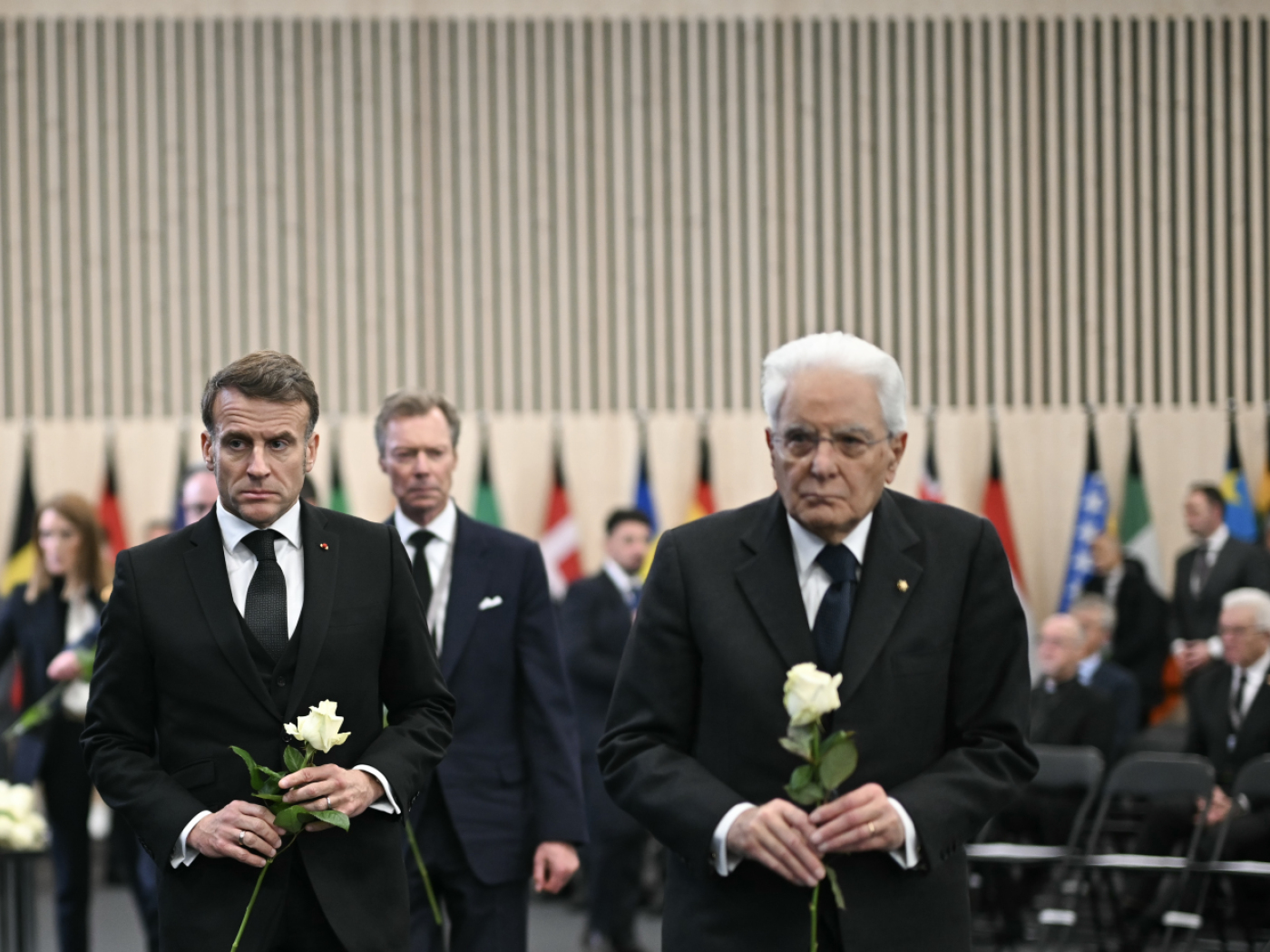 emmanuel macron e sergio mattarella alla cerimonia per le vittime di crans montana con rose bianche in mano