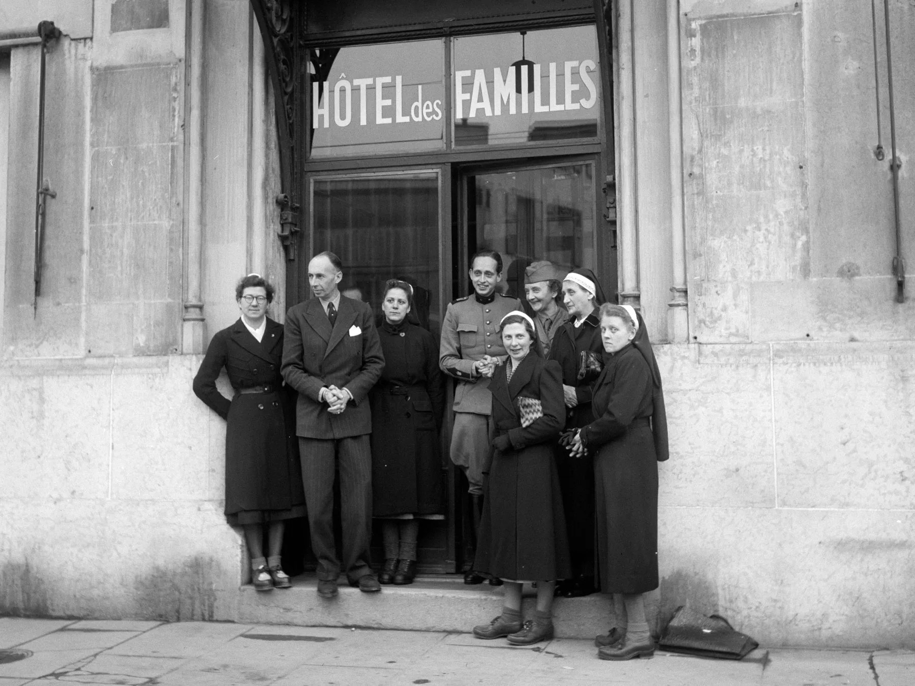 Frauen und Männer posieren vor einem Hotel (historisch)