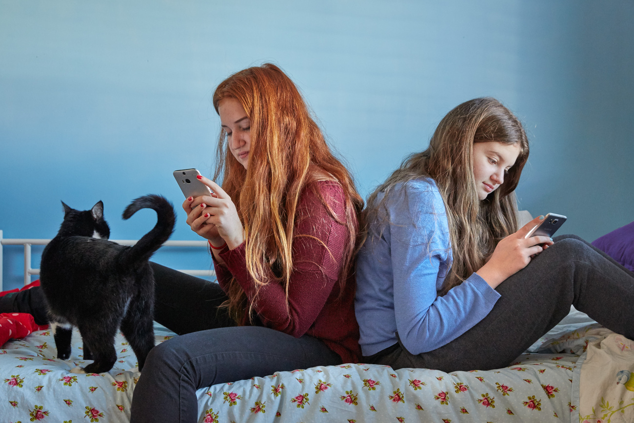 girls sitting on the bed with their mobile phones in their hands.
