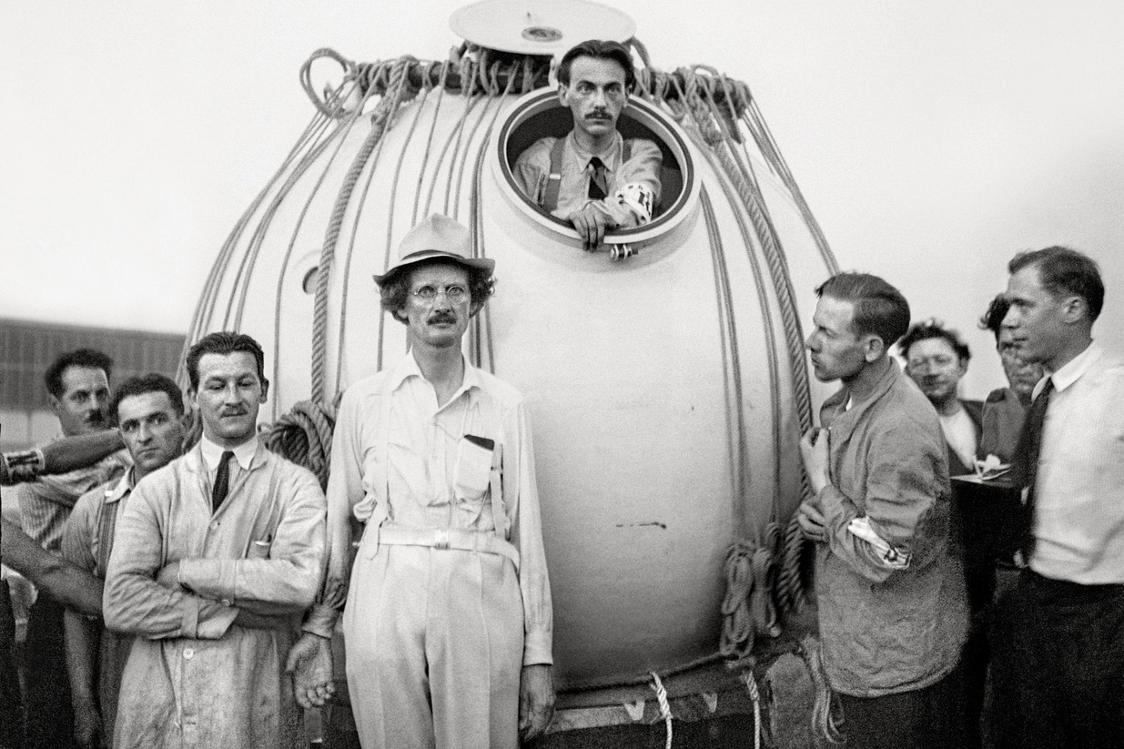 Uomini davanti a un veicolo di forma sferica, in bianco e nero