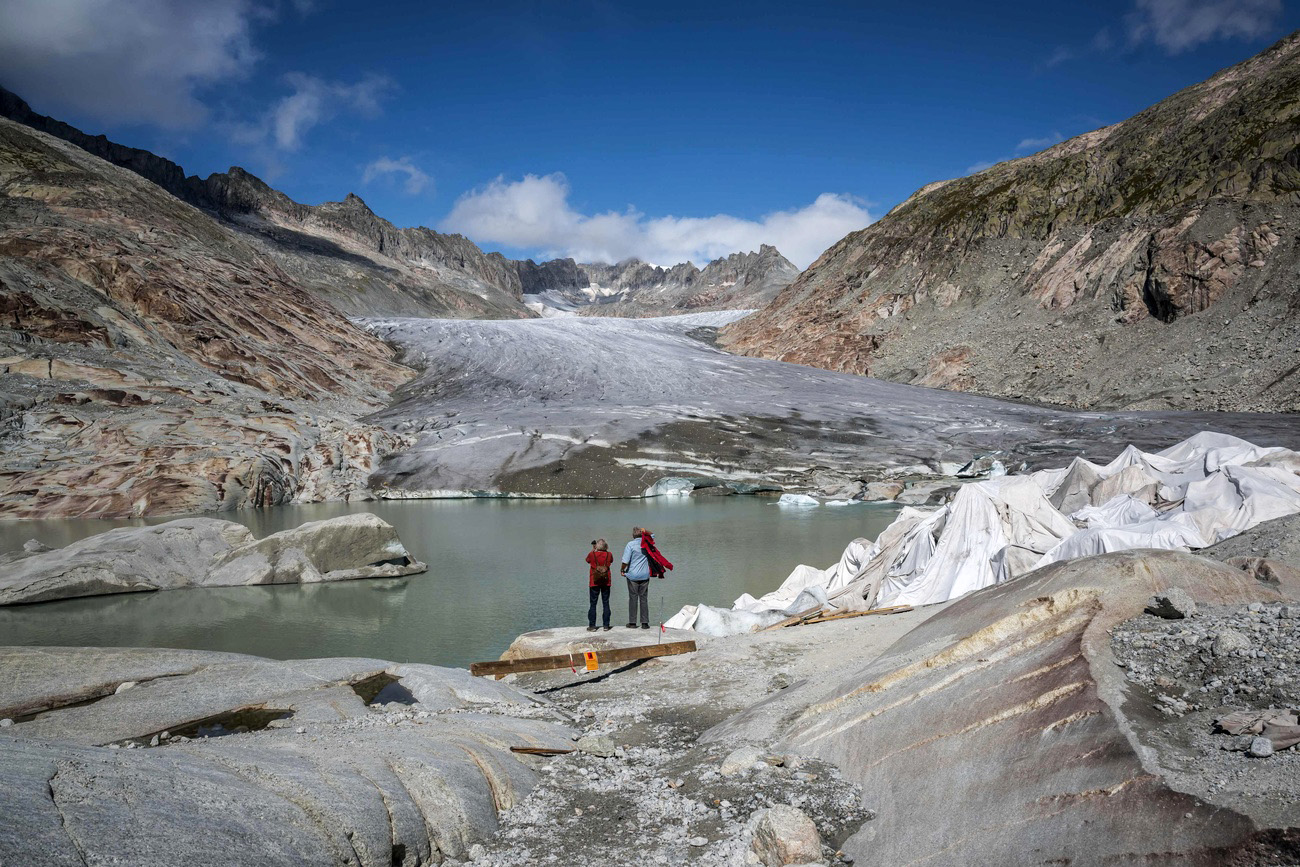 coppia sulla riva di un laghetto alpino sotto un ghiacciaio