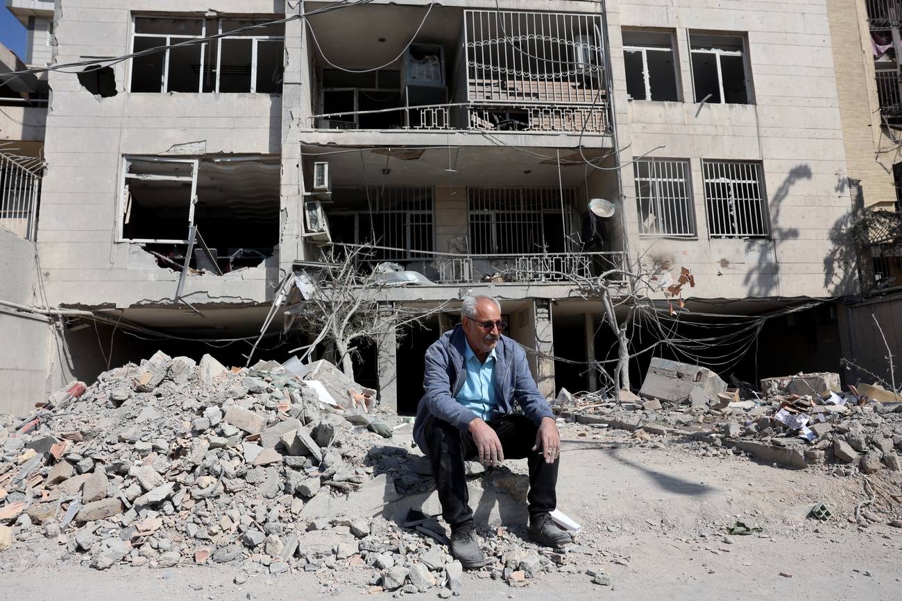 An Iranian man sits next to the damaged remains of his residential building in central Tehran on March 4.