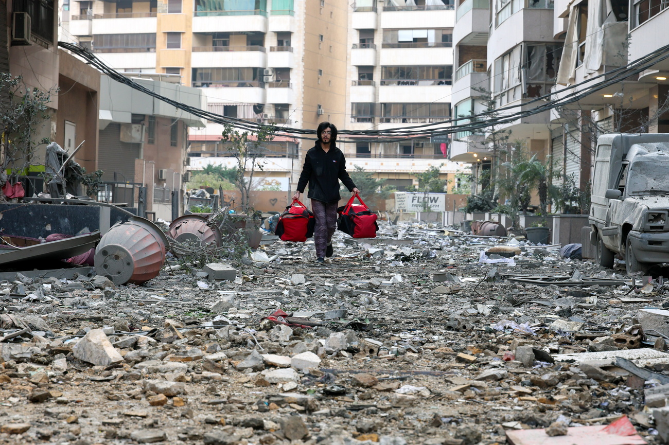 رجل لبناني يحمل أمتعته أثناء مغادرته حي الشياح في بيروت بعد غارة إسرائيلية، في ظل تصعيد يستهدف مواقع لحزب الله، وأسفر عن مئات القتلى والجرحى.