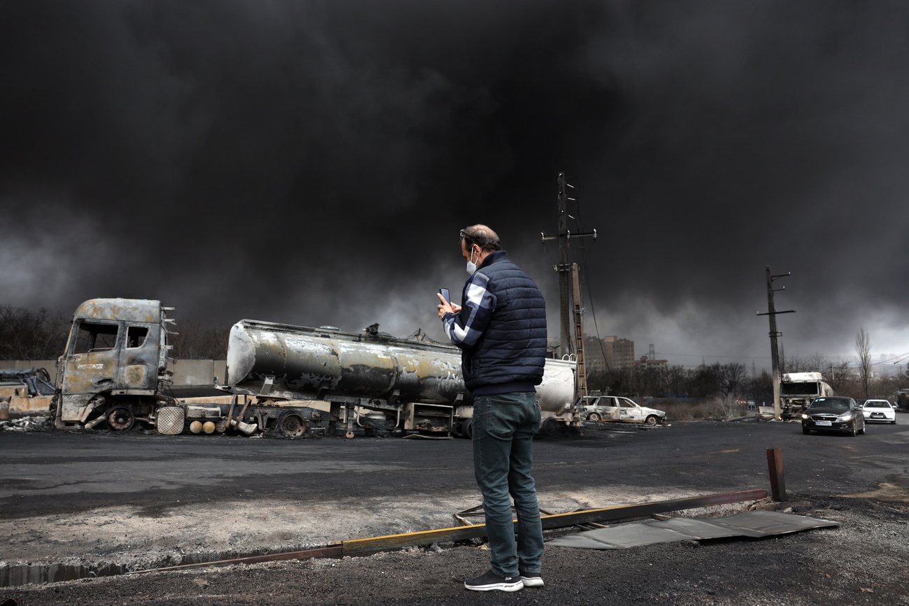 An Iranian man looks on as smoke rises from Shahran Oil Refinery following an airstrike in Tehran, Iran, March 8, 2026.
