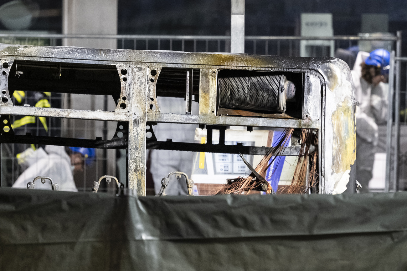 Fire investigators examine the charred shell of the completely burnt-out Postbus in Kerzers.