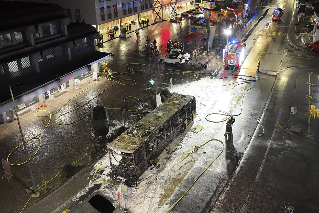 Photo of burnt bus in the street with police and firefighters
