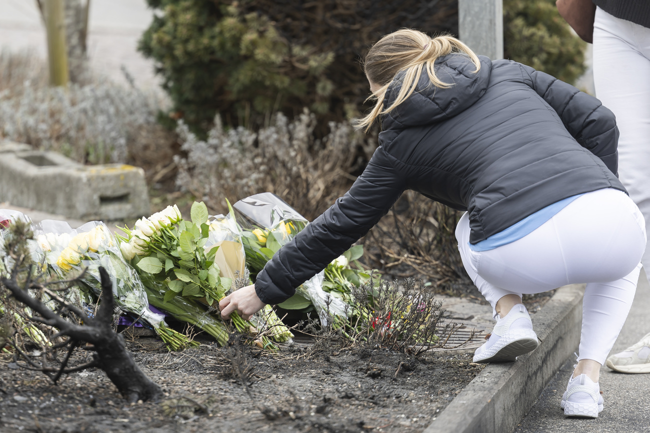 Photo of woman putting flowers on the street.
