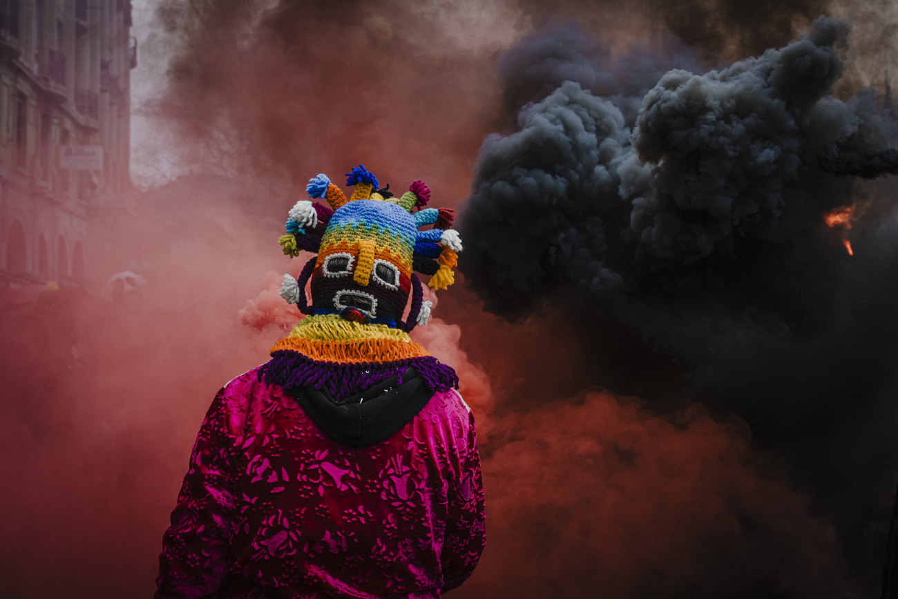 Persona mascherata di spalle davanti a fumo rosso