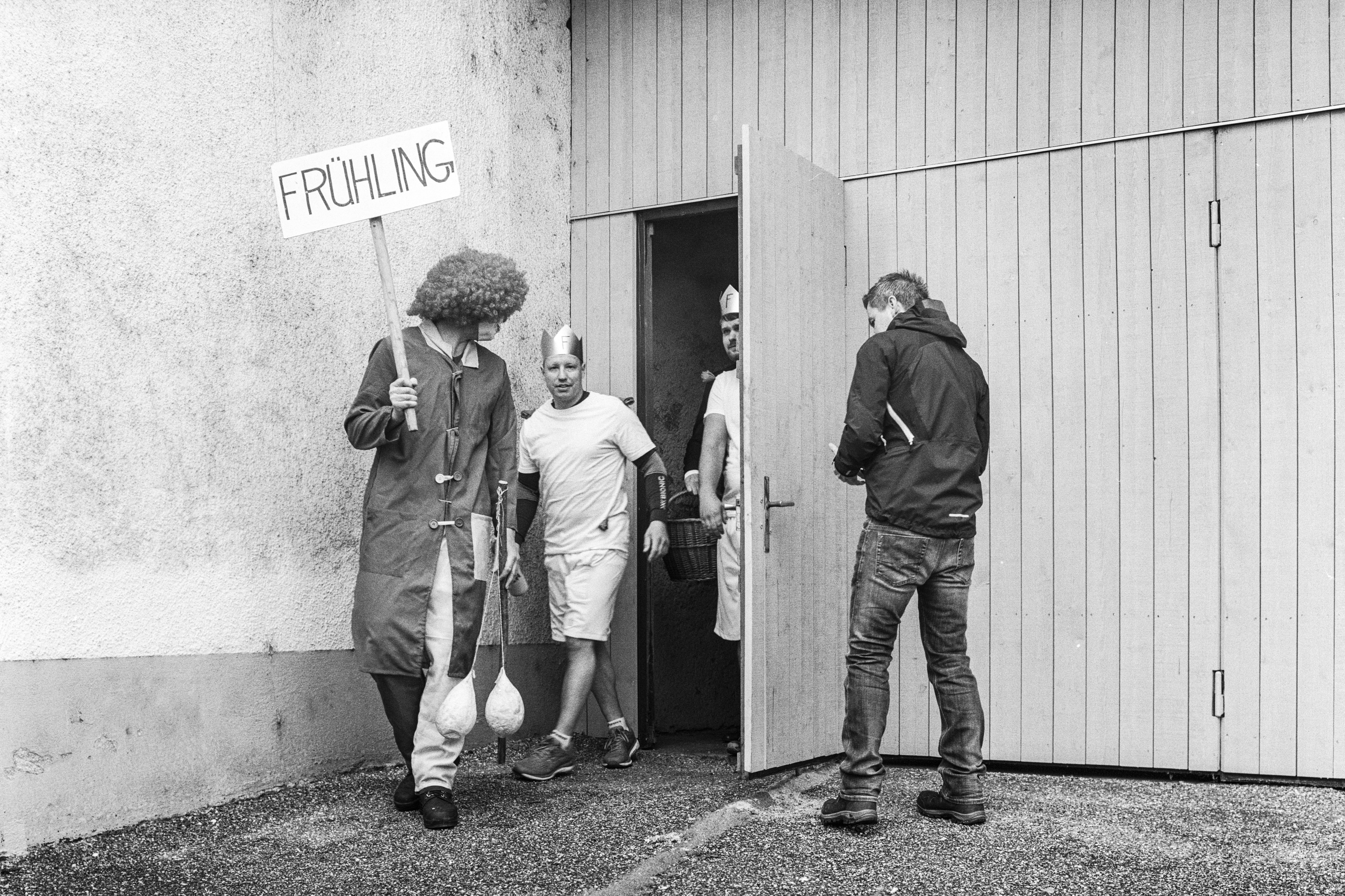 Menschen in Kostümen, einer Trägt ein Schild "Frühling"