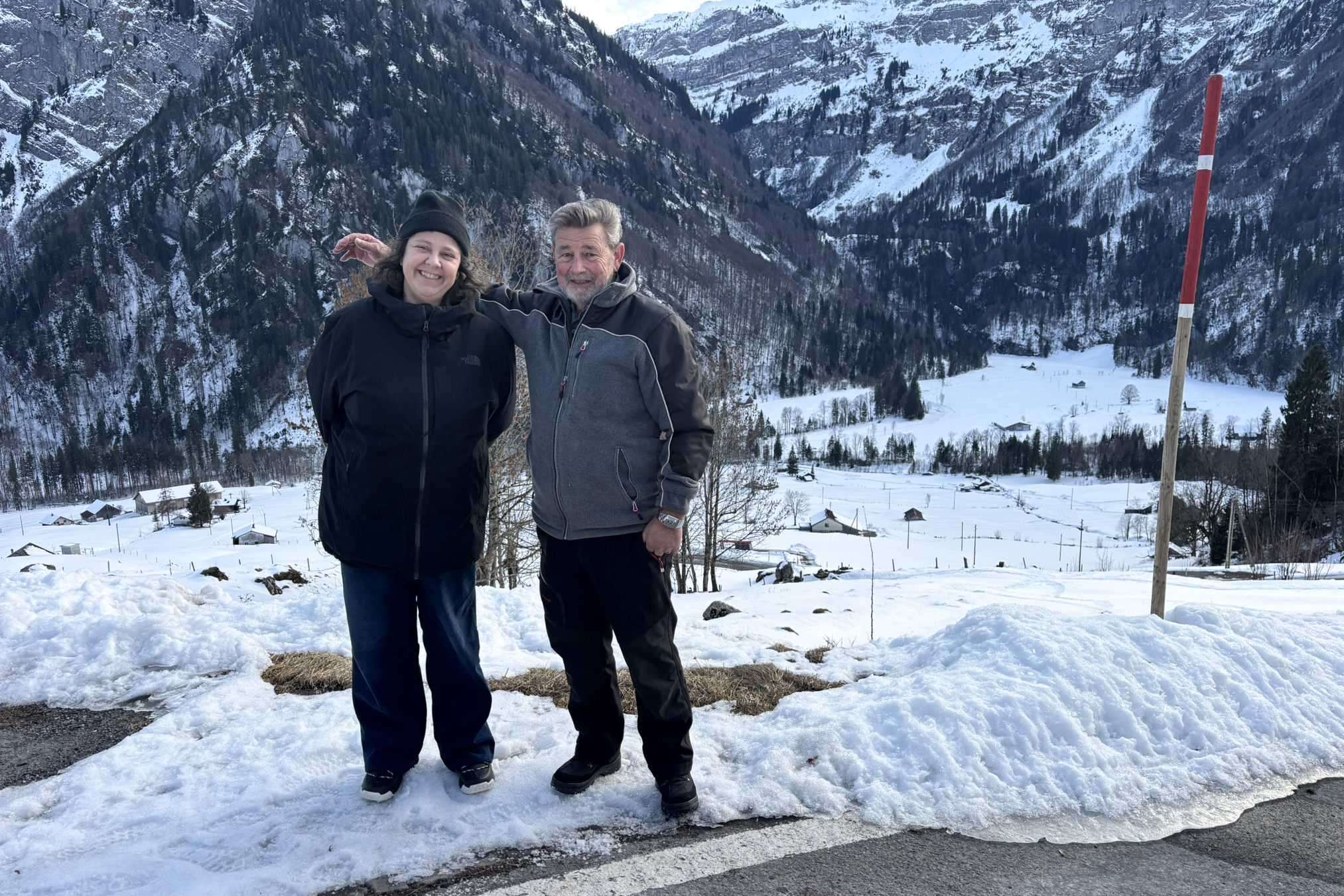 A man and a woman posing in front of a snowy valley.