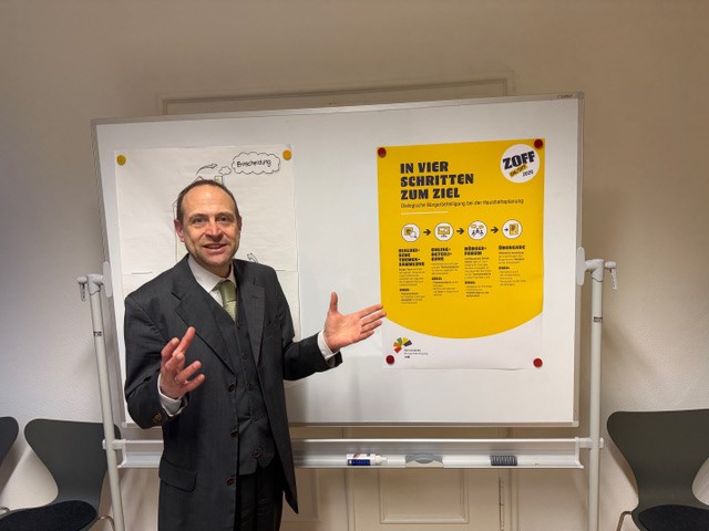 Ulrich Arndt steht vor einem Plakat.