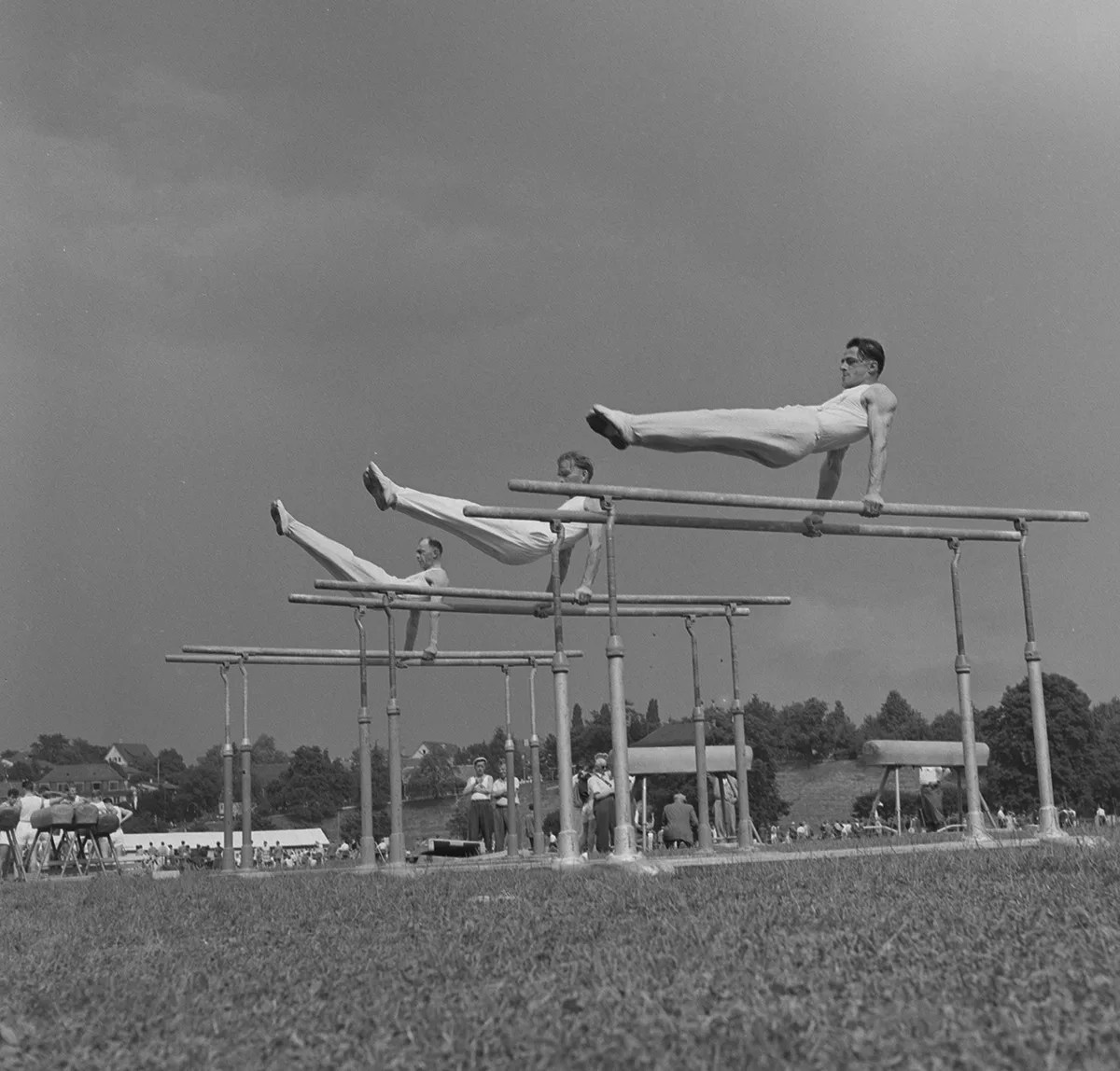 Trois gymnastes sur les barres parallèles