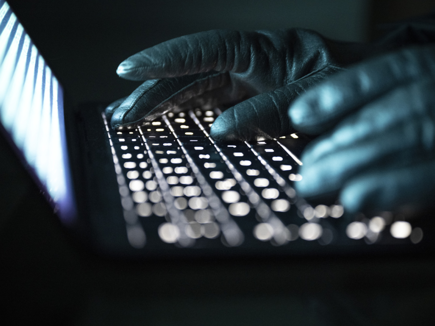 manicon guanti di pelle nera mentre scrivono sulla tastiera di un pc portatile