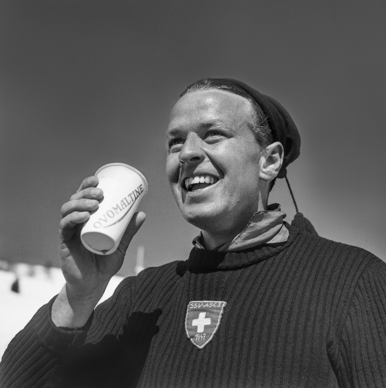 Sur une photo en noir et blanc, une personne boit de l'Ovomaltine.