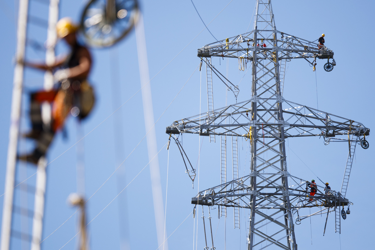Il personale posiziona una fune prima di tirare il cavo definitivo della linea elettrica, durante le operazioni di costruzione di una nuova linea aerea di Swissgrid da 220 kV nella zona industriale di Chandoline, a Sion.